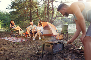 Image showing Party, camping of men and women group at forest. They relaxing, singing a song and cooking barbecue