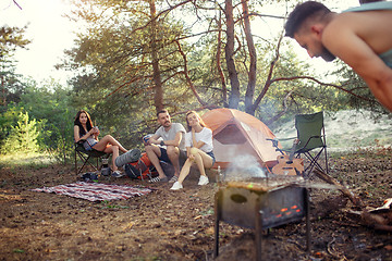 Image showing Party, camping of men and women group at forest. They relaxing, singing a song and cooking barbecue