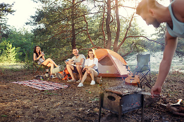 Image showing Party, camping of men and women group at forest. They relaxing, singing a song and cooking barbecue