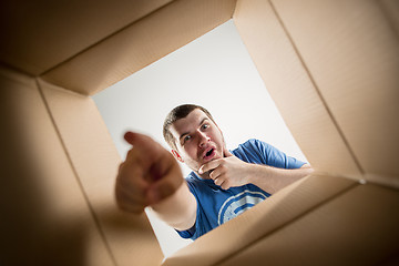 Image showing Man unpacking and opening carton box and looking inside