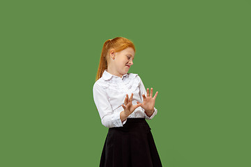 Image showing Doubtful pensive teen girl rejecting something against green background