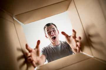 Image showing Man unpacking and opening carton box and looking inside