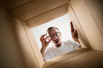 Image showing Man unpacking and opening carton box and looking inside