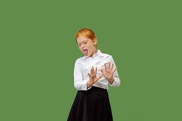 Image showing Doubtful pensive teen girl rejecting something against green background