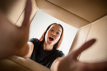 Image showing Woman unpacking and opening carton box and looking inside