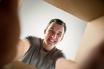 Image showing Man unpacking and opening carton box and looking inside