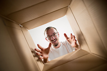 Image showing Man unpacking and opening carton box and looking inside