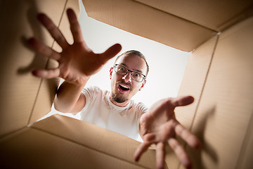 Image showing Man unpacking and opening carton box and looking inside