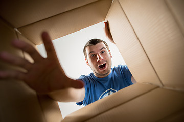 Image showing Man unpacking and opening carton box and looking inside