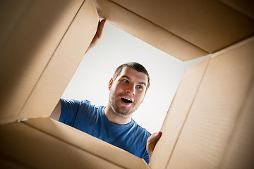 Image showing Man unpacking and opening carton box and looking inside