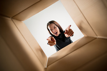 Image showing Woman unpacking and opening carton box and looking inside