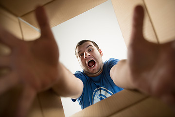 Image showing Man unpacking and opening carton box and looking inside