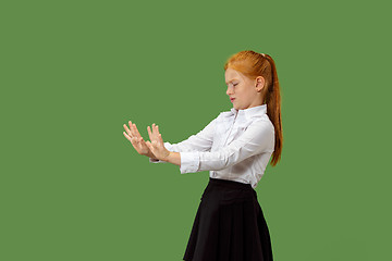 Image showing Doubtful pensive teen girl rejecting something against green background