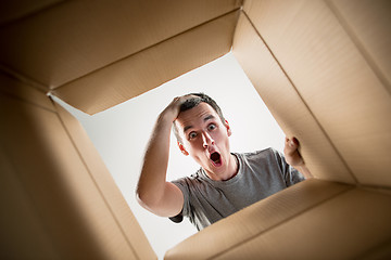 Image showing Man unpacking and opening carton box and looking inside