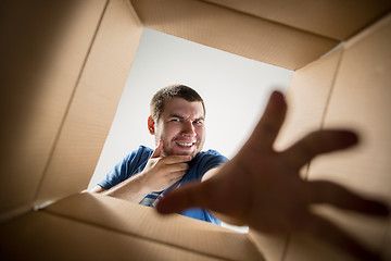 Image showing Man unpacking and opening carton box and looking inside