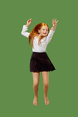 Image showing Young happy caucasian teen girl jumping in the air , isolated on green background