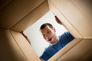 Image showing Man unpacking and opening carton box and looking inside