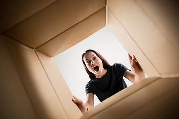 Image showing Woman unpacking and opening carton box and looking inside