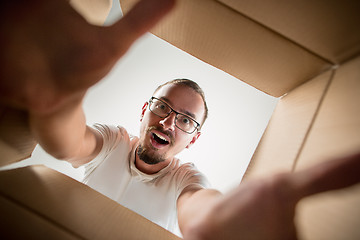 Image showing Man unpacking and opening carton box and looking inside