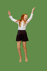 Image showing Young happy caucasian teen girl jumping in the air , isolated on green background