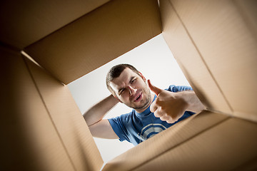 Image showing Man unpacking and opening carton box and looking inside