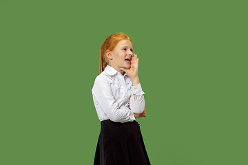 Image showing The young teen girl whispering a secret behind her hand over green background