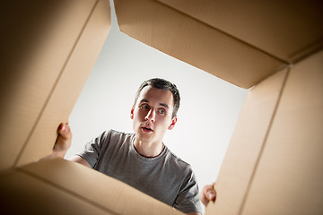 Image showing Man unpacking and opening carton box and looking inside