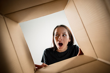 Image showing Woman unpacking and opening carton box and looking inside