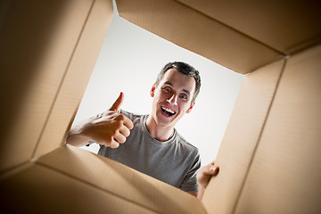 Image showing Man unpacking and opening carton box and looking inside