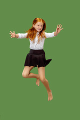 Image showing Young happy caucasian teen girl jumping in the air , isolated on green background