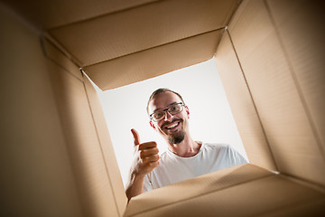 Image showing Man unpacking and opening carton box and looking inside