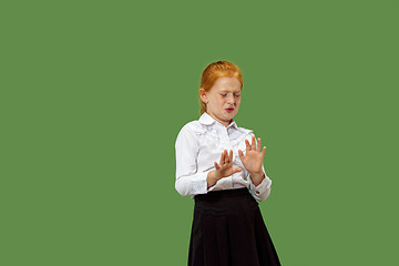 Image showing Doubtful pensive teen girl rejecting something against green background