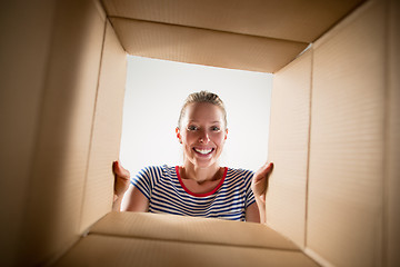 Image showing Woman unpacking and opening carton box and looking inside