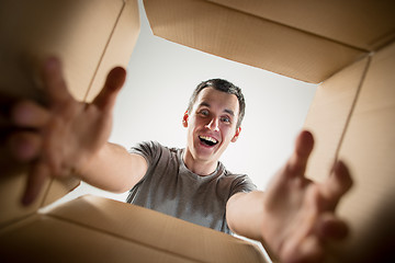 Image showing Man unpacking and opening carton box and looking inside