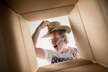 Image showing Man unpacking and opening carton box and looking inside