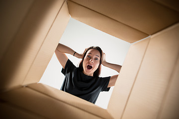 Image showing Woman unpacking and opening carton box and looking inside