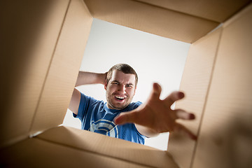 Image showing Man unpacking and opening carton box and looking inside