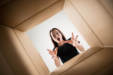 Image showing Woman unpacking and opening carton box and looking inside