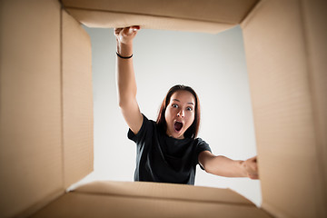 Image showing Woman unpacking and opening carton box and looking inside