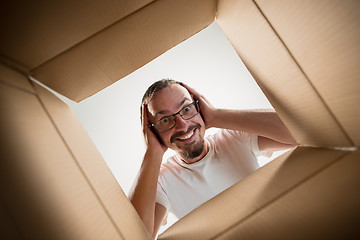 Image showing Man unpacking and opening carton box and looking inside