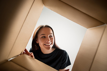 Image showing Woman unpacking and opening carton box and looking inside