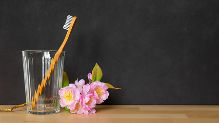 Image showing a wooden toothbrush in a glass on black background