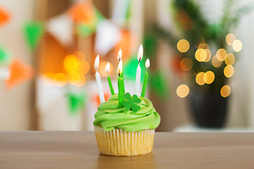 Image showing green cupcake with six burning candles on table