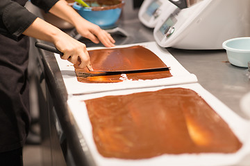 Image showing confectioner makes chocolate dessert at sweet-shop