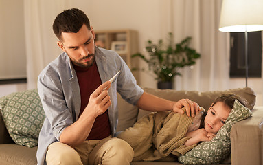 Image showing father with thermometer and ill daughter at home