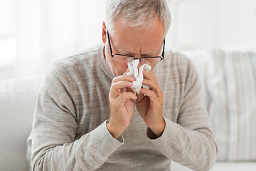 Image showing sick senior man with paper wipe blowing his nose