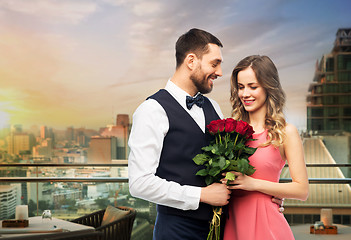 Image showing happy couple with red roses over restaurant lounge