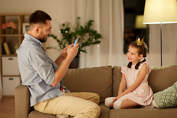 Image showing father photographing daughter by cellphone at home