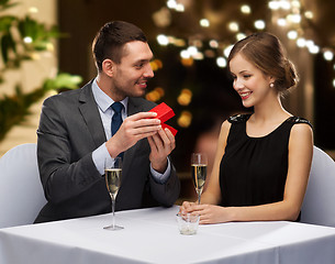 Image showing man showing woman present in red box at restaurant