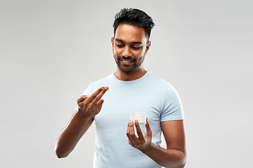 Image showing happy indian man applying cream to face